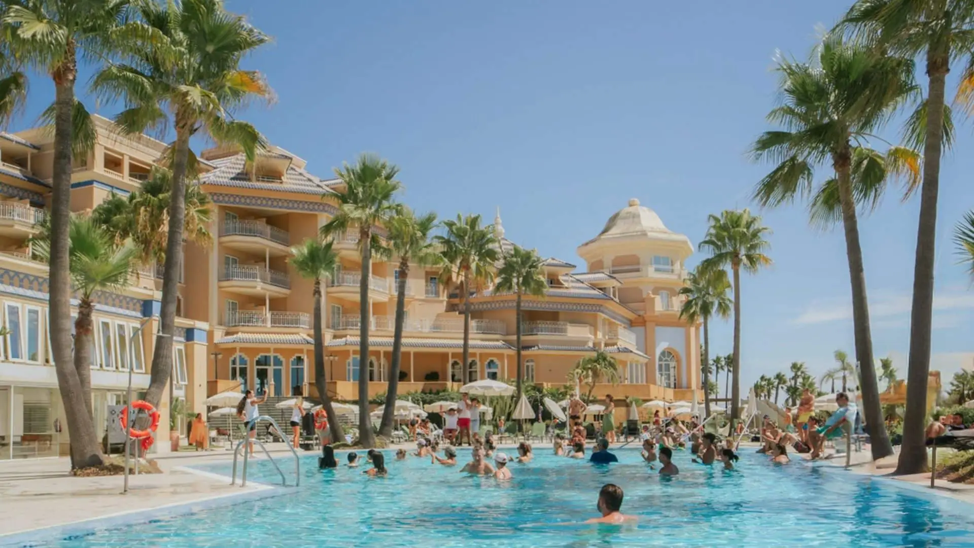 Guests enjoying the pool at Meliá Isla Canela surrounded by palm trees